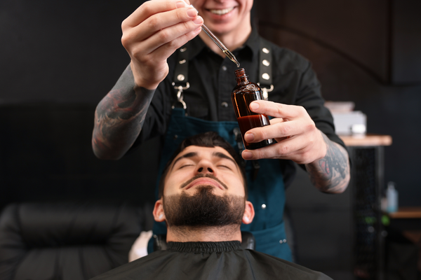 barber using urth's beard oil on client