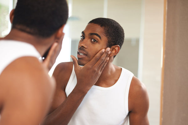 young black man using ingrown hair serum on face