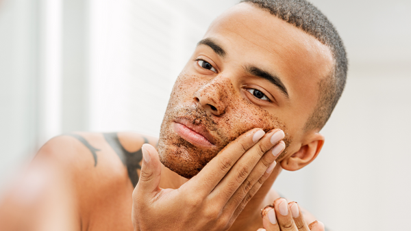 handsome black man with tattoo applying natural face scrub 